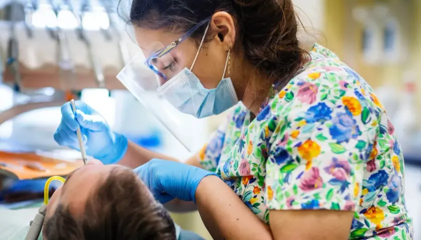 Dentystka w maseczce i okularach ochronnych wykonuje zabieg podniesienia dna zatoki szczękowej.