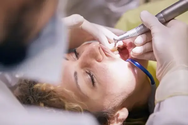 Pacjentka u dentysty, trwa zabieg. Czy leczenie kanałowe jest na NFZ? Warto sprawdzić, bo czasem można zaoszczędzić.
